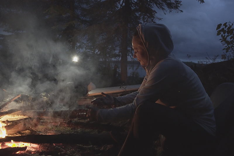 anne-marie losique assise devant un feu de camp dans expédition extreme