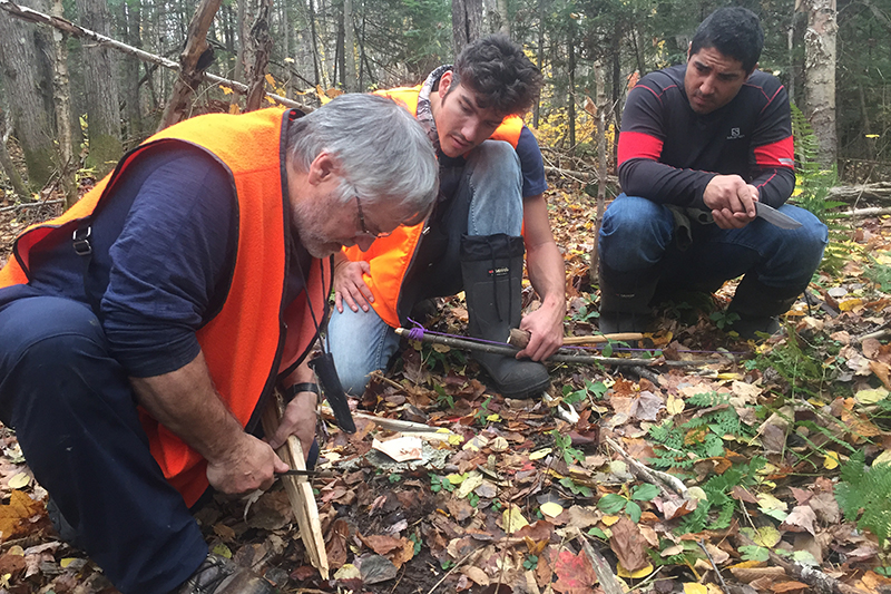 francis bouillon, jason roy-leveillée et le guide de survie en forêt d'expédition extrême accroupis pour fabriquer une arme en bois